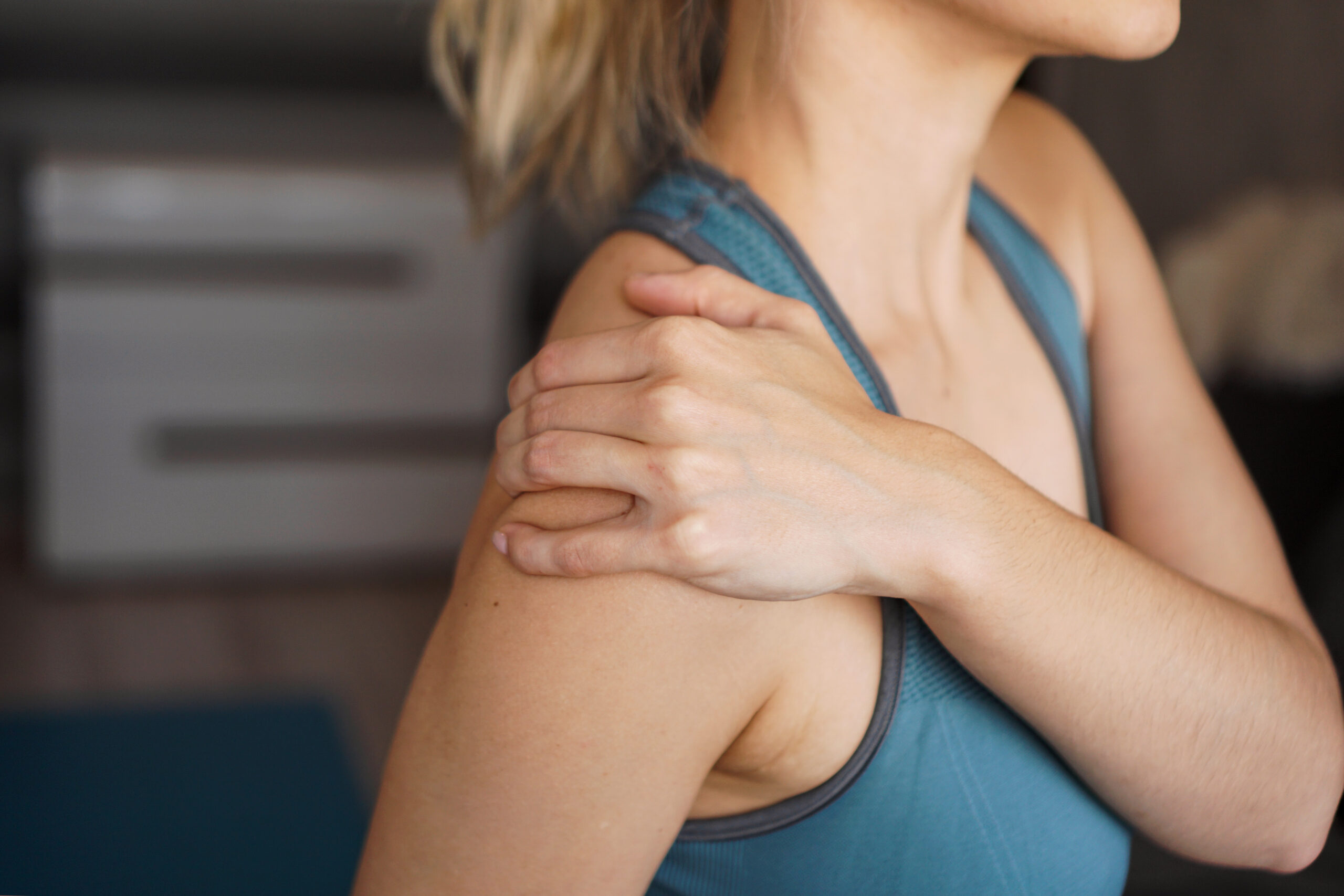 Woman holding her shoulder while experiencing shoulder pain